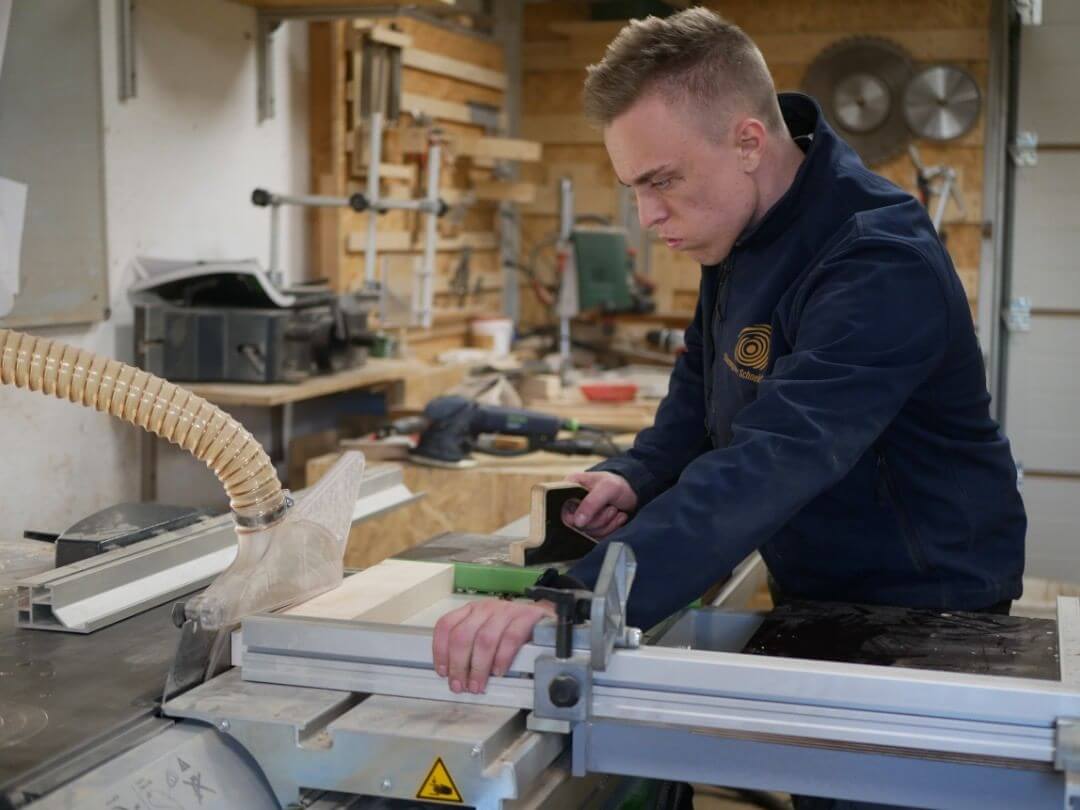 Felix Picherer trennt ein Stück Ahorn auf der Formatkreissäge auf, während er präzise das Holz für die Produktion von Schneidebrettern vorbereitet